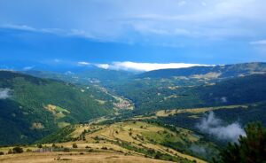 Vall verda amb muntanyes sota un cel blau. FCVC expert en subvencions per negocis rurals.